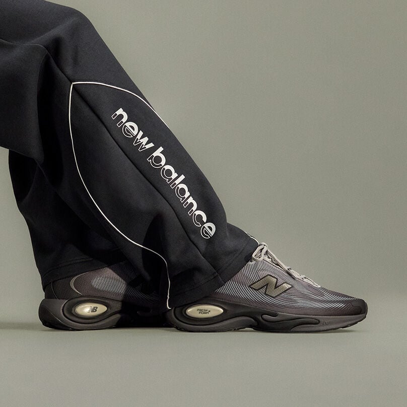 Close-up studio image focusing on a person&rsquo;s lower legs and feet positioned against a plain light gray background.