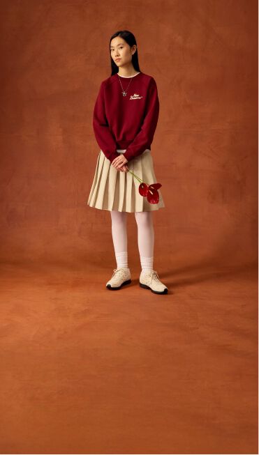 Man standing with beige sweater and hands up his pockets.