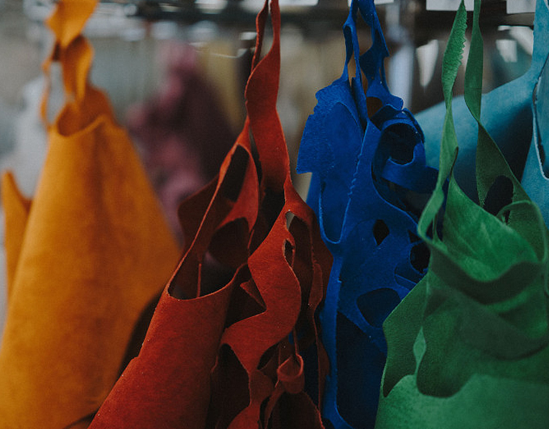 Different colored leathers hanging from rack in factory