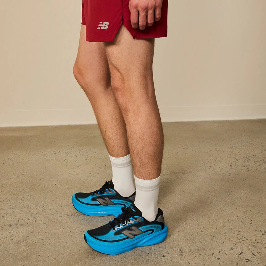 Close-up studio image of a person kneeling on one knee against a smooth, neutral gray background.