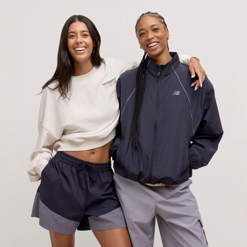 Two women standing together against a cream studio backdrop.