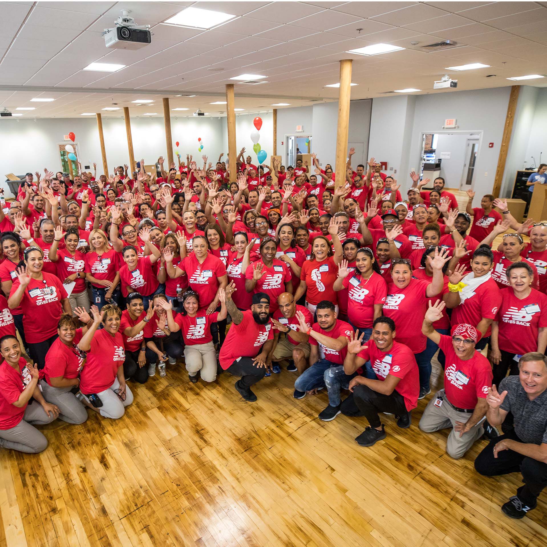 Large group of New Balance employees smiling and waving at camera