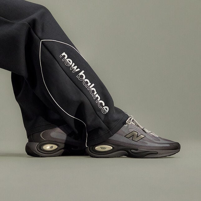 Close-up studio image focusing on a person&rsquo;s lower legs and feet positioned against a plain light gray background.