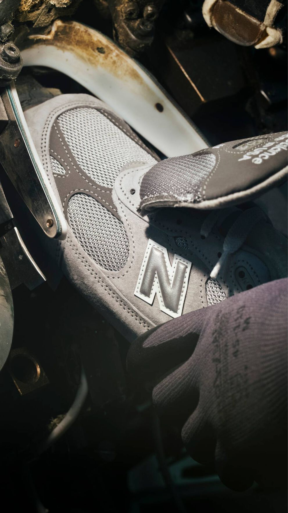 A hand putting a sneaker into a machine during its construction.  