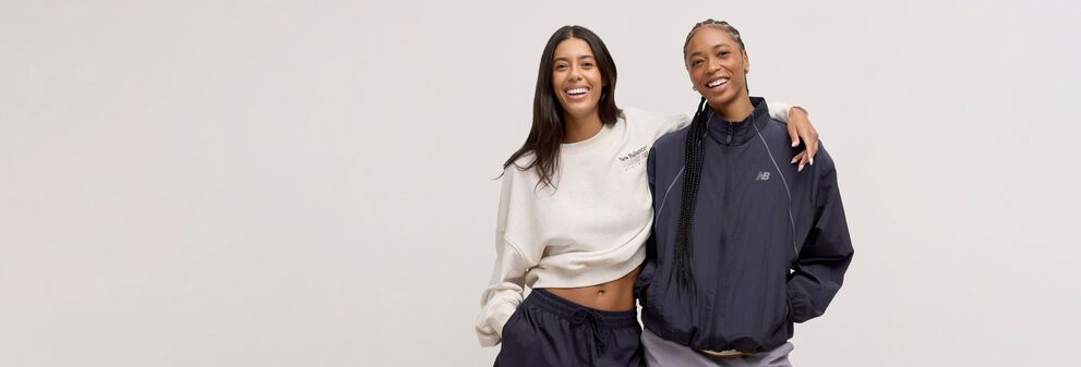 Two woman standing back to back and looking at the viewer.