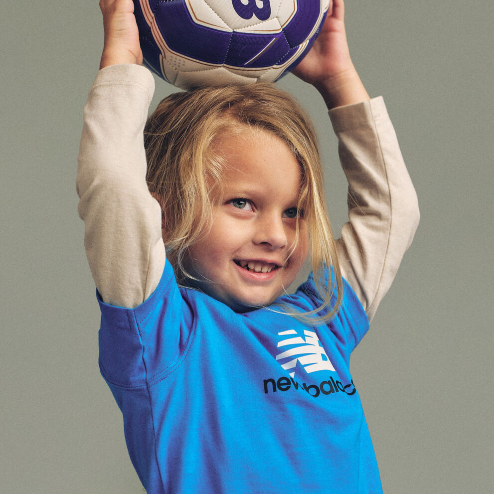 Close-up studio image of a child holding a blue, white, and purple soccer ball above the head with both hands.